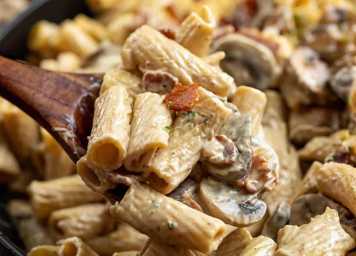 This mushroom and bacon rigatoni is a rich, creamy pasta made with crispy bacon, sautéed mushrooms, and a silky Parmesan cream sauce. It’s hearty, comforting, and full of deep savory flavor, with a touch of lemon to keep it balanced. Wooden spoon with Mushroom and Bacon Rigatoni on it, very close up.