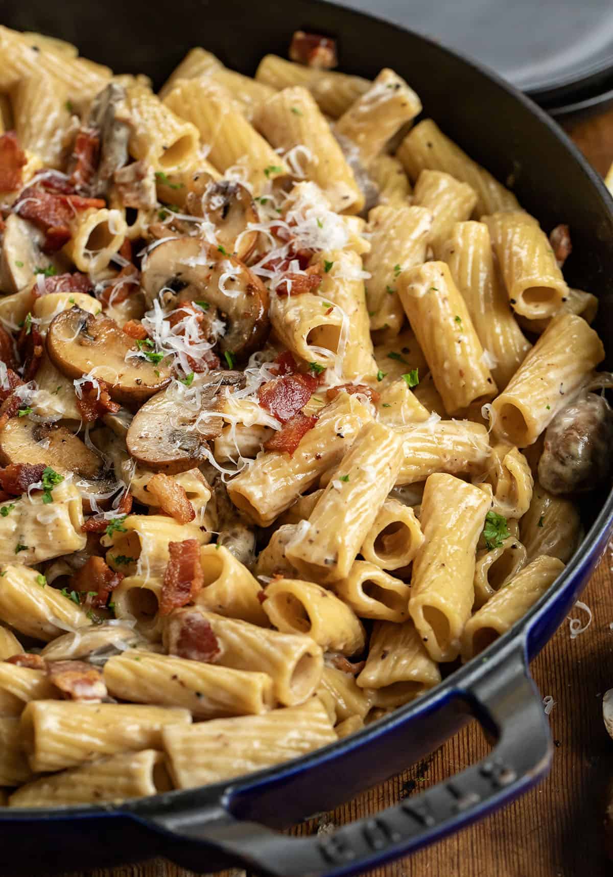 This mushroom and bacon rigatoni is a rich, creamy pasta made with crispy bacon, sautéed mushrooms, and a silky Parmesan cream sauce. It’s hearty, comforting, and full of deep savory flavor, with a touch of lemon to keep it balanced. Close up of a pan of Mushroom and Bacon Rigatoni showing creamy noodles.