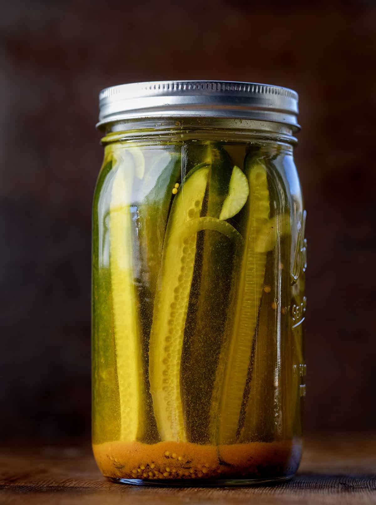 These Mustard Pickles are crisp, sweet, and tangy with a bold mustard flavor and that signature golden color. They’re incredibly easy to make with a simple hot brine and no canning required; just pour, chill, and let the flavors develop in the refrigerator! One jar of Mustard Pickles on a wooden table.