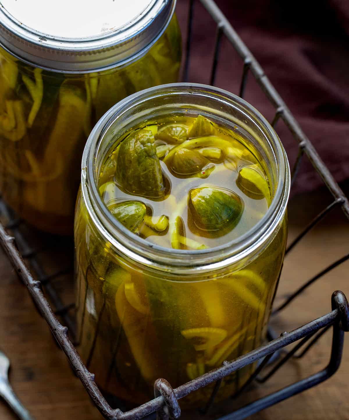 These Mustard Pickles are crisp, sweet, and tangy with a bold mustard flavor and that signature golden color. They’re incredibly easy to make with a simple hot brine and no canning required; just pour, chill, and let the flavors develop in the refrigerator! Open jar of Mustard Pickles in a basket on a wooden table.