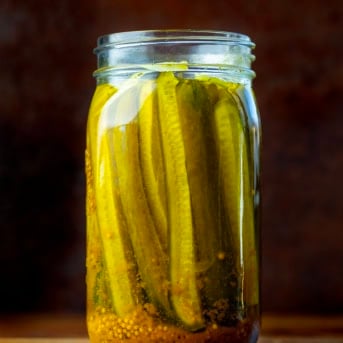 Open jar of Mustard Pickles on a wooden table.