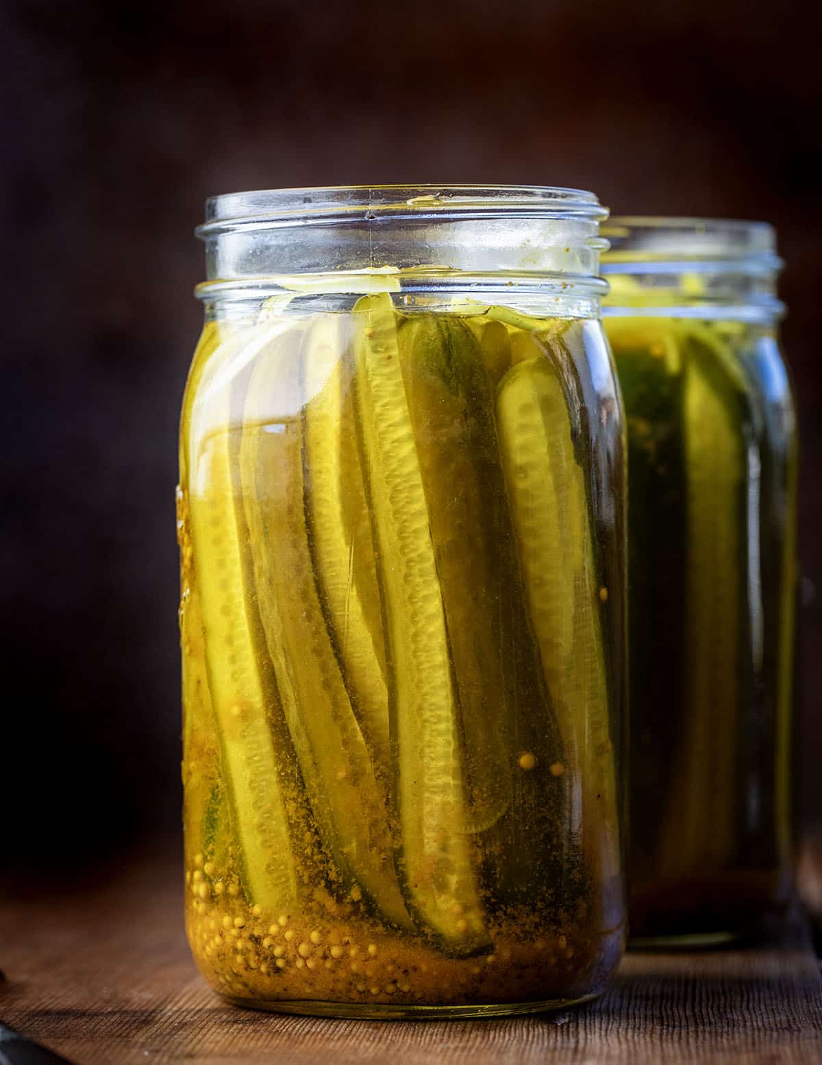 These Mustard Pickles are crisp, sweet, and tangy with a bold mustard flavor and that signature golden color. They’re incredibly easy to make with a simple hot brine and no canning required; just pour, chill, and let the flavors develop in the refrigerator! Jars of Mustard Pickles on a wooden table.