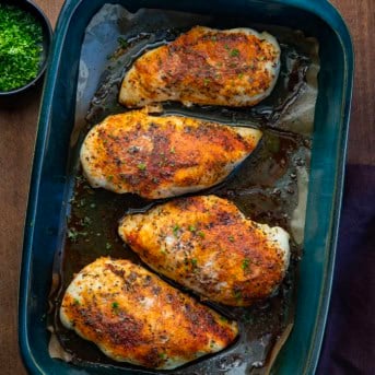 Pan of Oven Baked Chicken Breasts on a wooden table from overhead.