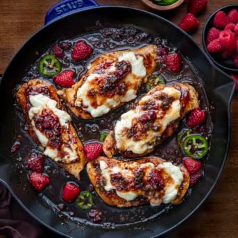 Raspberry Jalapeño Cream Cheese Chicken in a skillet on wooden table from overhead.