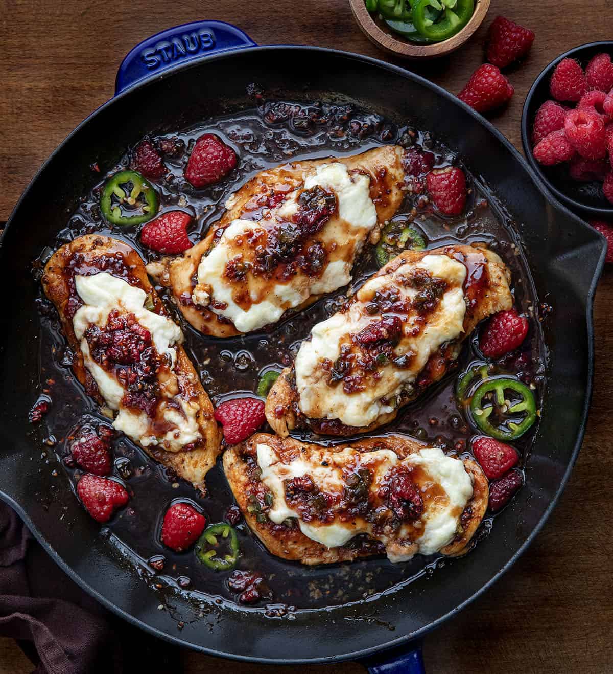 Raspberry Jalapeño Cream Cheese Chicken in a skillet on wooden table from overhead.