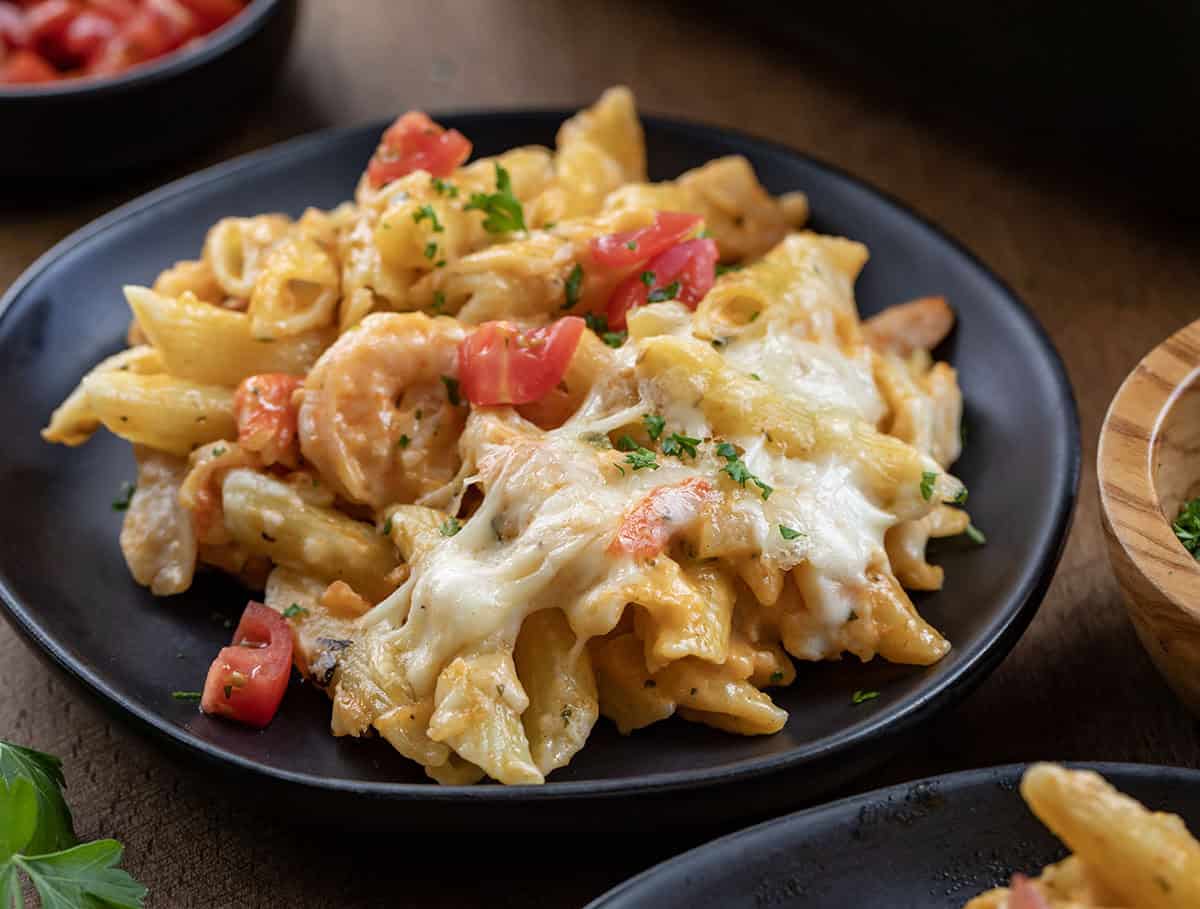 This Creamy Seafood Pasta Bake is a rich, comforting baked pasta loaded with tender shrimp, imitation crab, and a creamy Monterey Jack cheese sauce. It’s baked until bubbly and golden on top, making it an easy yet impressive dinner that’s perfect for seafood lovers! Seafood Pasta Bake on a black plate on a wooden table.