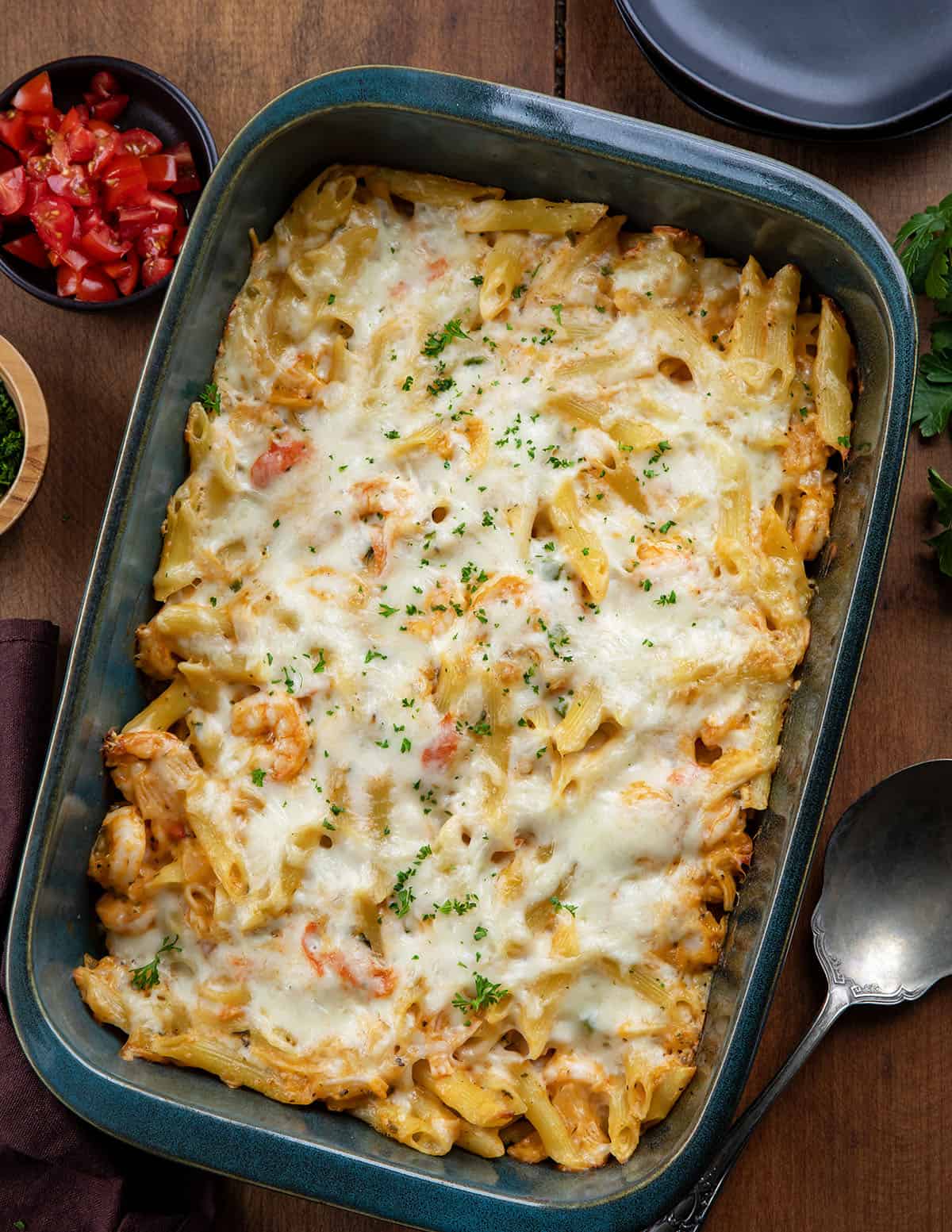This Creamy Seafood Pasta Bake is a rich, comforting baked pasta loaded with tender shrimp, imitation crab, and a creamy Monterey Jack cheese sauce. It’s baked until bubbly and golden on top, making it an easy yet impressive dinner that’s perfect for seafood lovers! Pan of Seafood Pasta Bake on a wooden table from overhead.