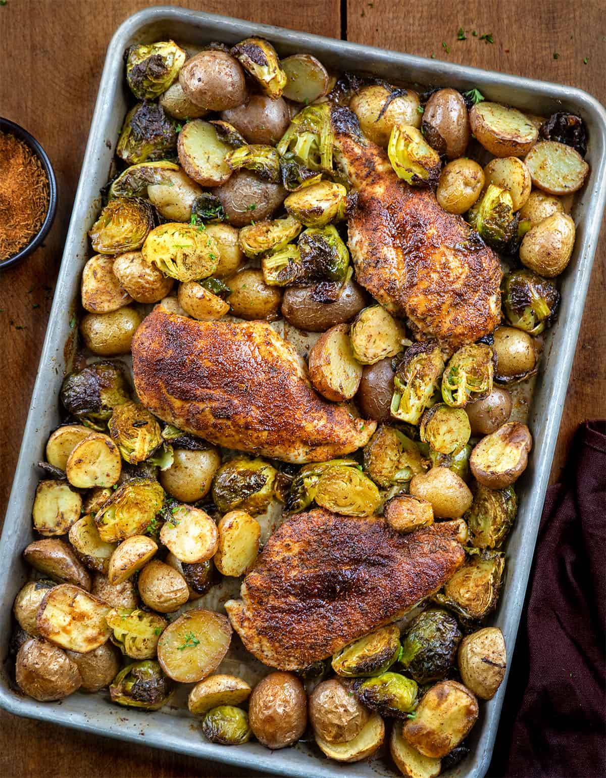 One pan Blackened Chicken and Brussels Sprouts on a wooden table from overhead One pan Blackened Chicken and Brussels Sprouts on a wooden table from overhead.