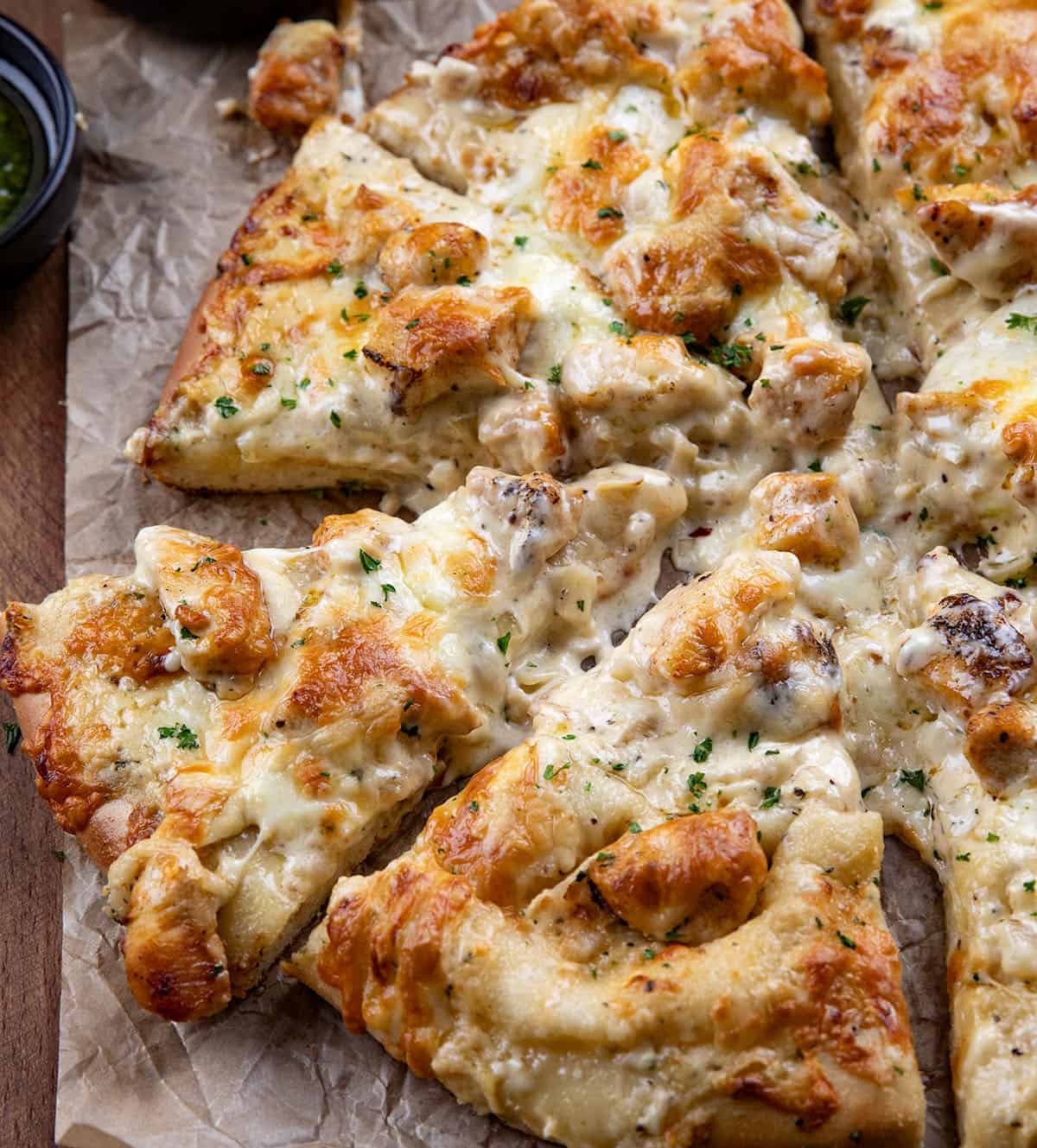 I loved my Chicken Alfredo Garlic Bread so much, I had to make this Chicken Alfredo Pizza, too! It takes everything you love about creamy Alfredo sauce, tender chicken, and melty cheese, and piles it all onto a soft homemade pizza dough that bakes up golden and irresistible! Close up of cut pieces of Chicken Alfredo Pizza.