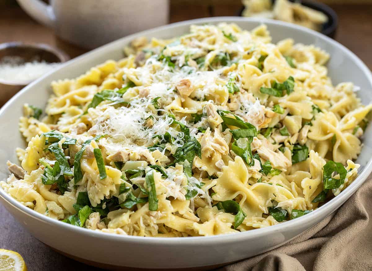 This Lemon Parmesan Pasta Salad with Chicken is a light, fresh pasta salad made with tender chicken, pasta, parmesan, and a bright lemon-garlic vinaigrette! Serving platter of Chicken Lemon Parmesan Pasta Salad on a wooden table.