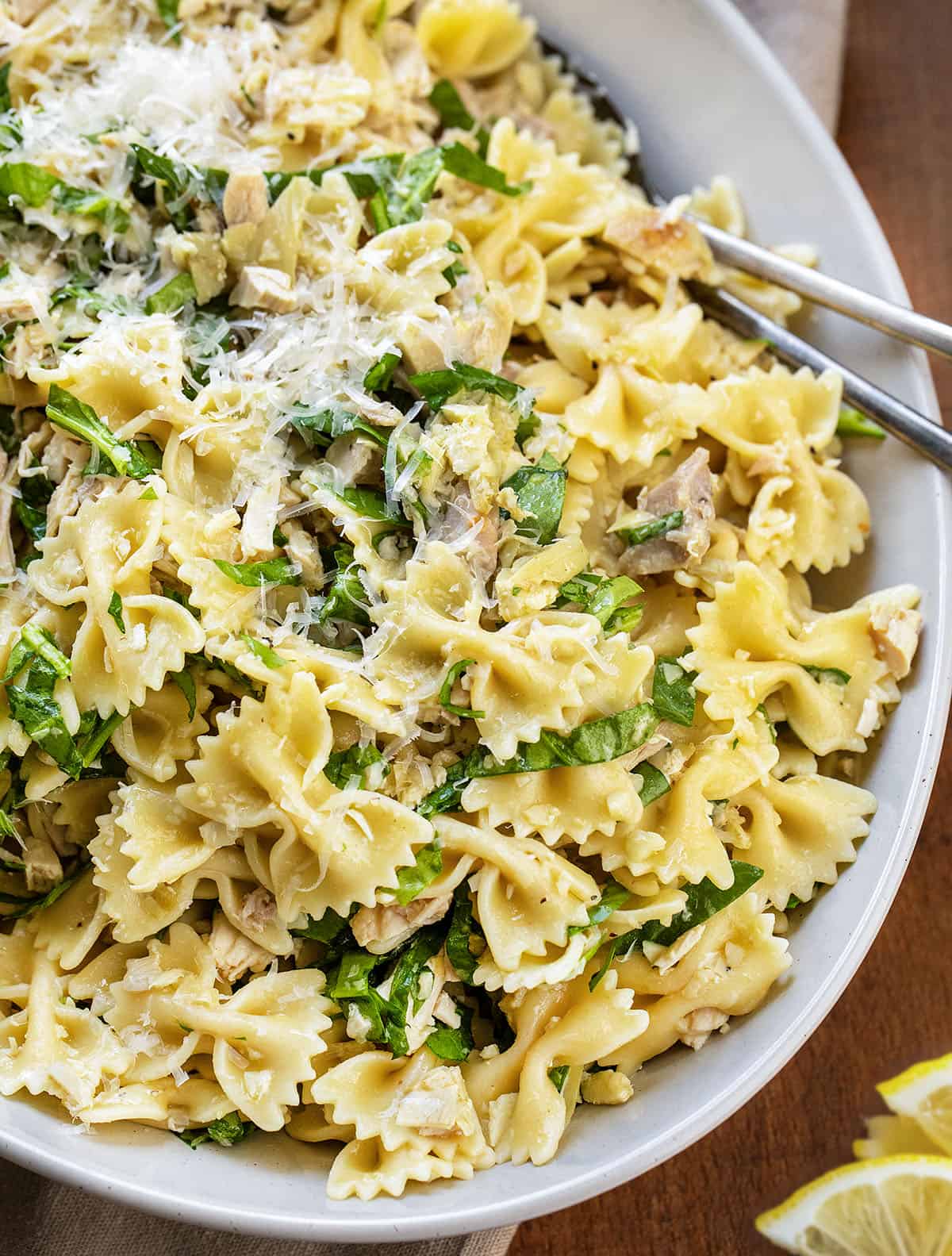 This Lemon Parmesan Pasta Salad with Chicken is a light, fresh pasta salad made with tender chicken, pasta, parmesan, and a bright lemon-garlic vinaigrette! Close up of Chicken Lemon Parmesan Pasta Salad in a dish on a wooden table.