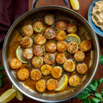 Cowboy Butter Scallops in a skillet on a wooden table from overhead.