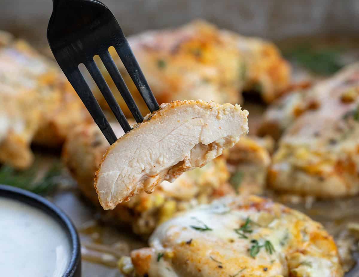 If you love pickles and ranch, this Dill Pickle Ranch Chicken is about to be your new obsession! Juicy chicken thighs are soaked in dill pickle juice for maximum tang and tenderness, then brushed with my creamy homemade Dill Pickle Ranch Dressing and cooked until perfectly golden! Piece of Dill Pickle Ranch Chicken showing the juicy chicken.