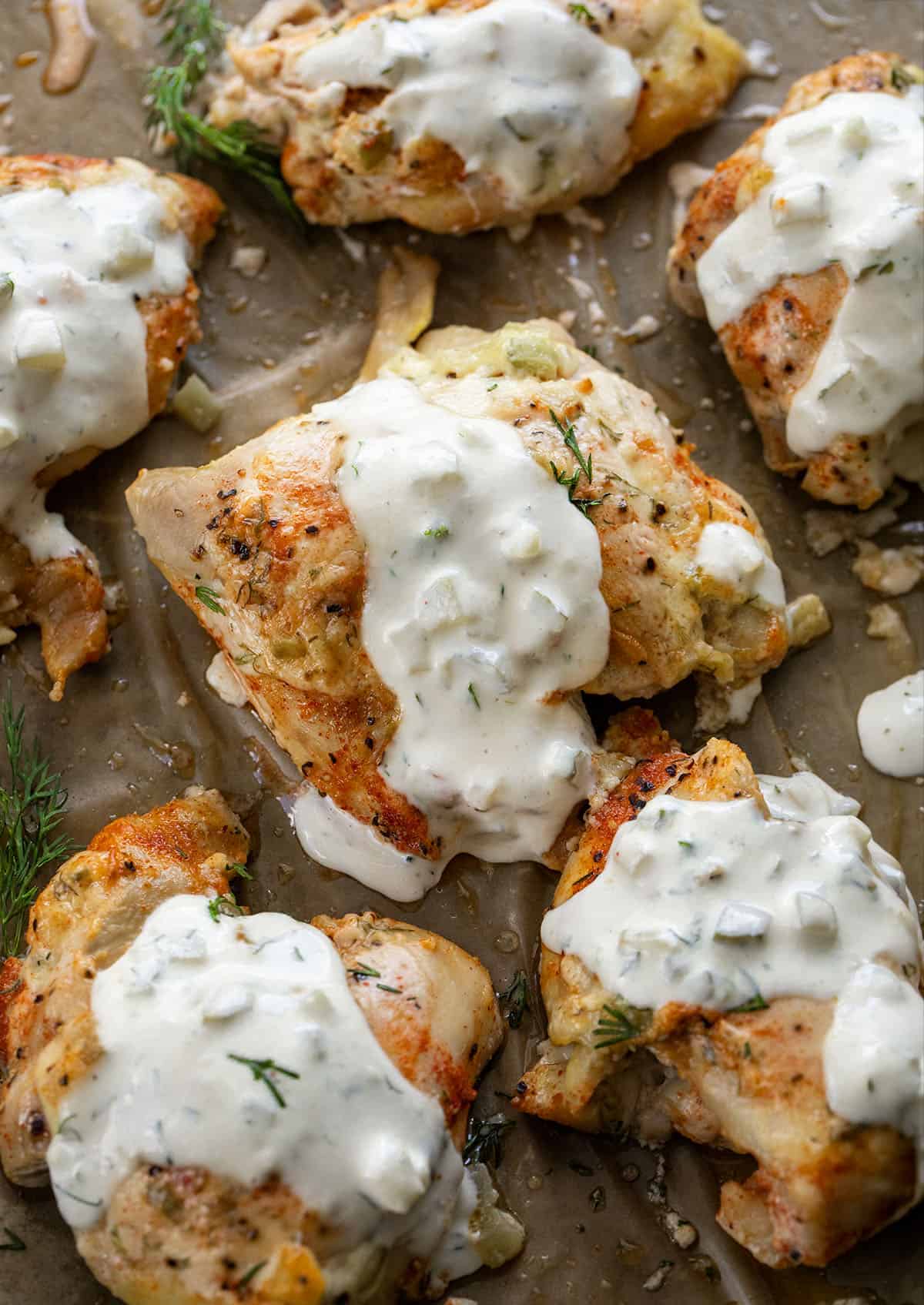 If you love pickles and ranch, this Dill Pickle Ranch Chicken is about to be your new obsession! Juicy chicken thighs are soaked in dill pickle juice for maximum tang and tenderness, then brushed with my creamy homemade Dill Pickle Ranch Dressing and cooked until perfectly golden! Dill Pickle Ranch Chicken close up drizzled with Dill Pickle Ranch Dressing.