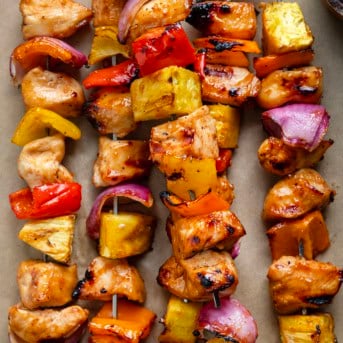 Close up of Hawaiian Chicken Skewers on tan parchment paper.