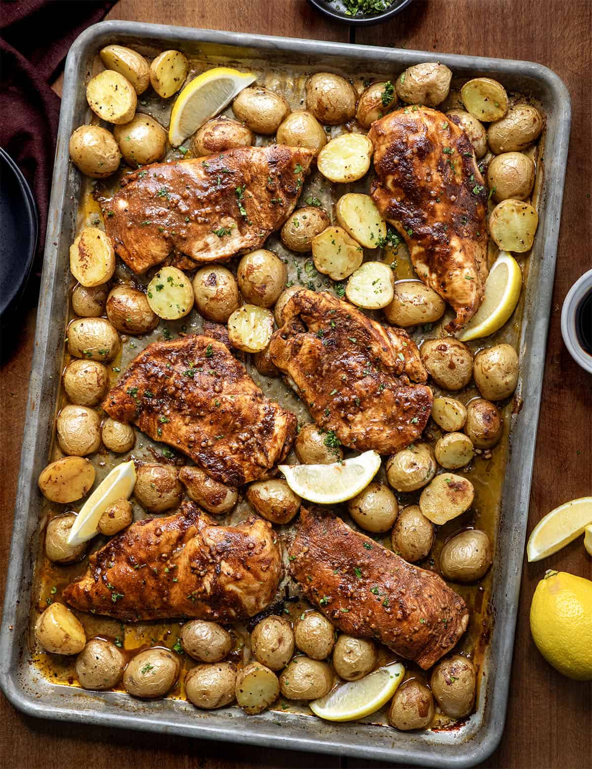 Juicy chicken and golden potatoes to a simple balsamic-lemon glaze that coats everything as it bakes Lemon Balsamic Chicken and Potatoes on a sheet pan on a wooden table from overhead.