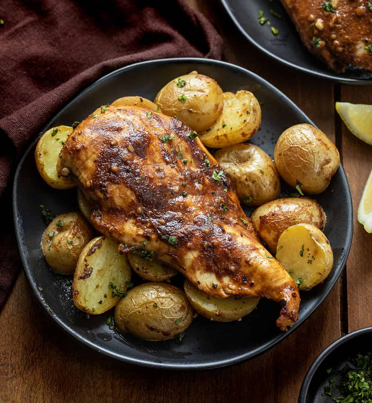 Juicy chicken and golden potatoes to a simple balsamic-lemon glaze that coats everything as it bakes Black plates with Lemon Balsamic Chicken and Potatoes on them.