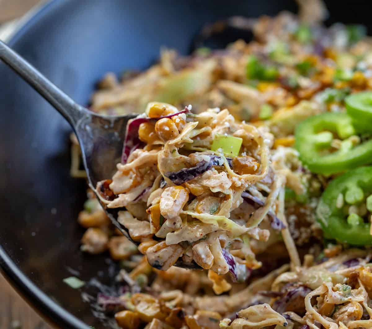 This Mexican Street Corn Slaw is a fresh, crunchy side dish inspired by classic elote. It’s made with shredded cabbage, sweet corn, a creamy lime dressing, and just the right amount of spice! Spoonful of Mexican Street Corn Slaw very close up.