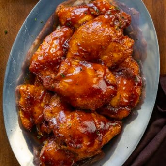 Platter of Oven Baked BBQ Chicken Thighs on a wooden table from overhead.