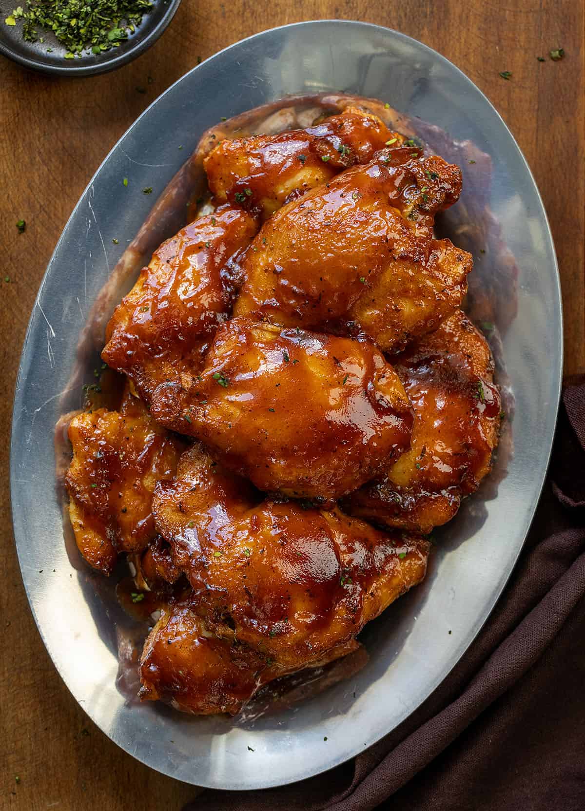 Platter of Oven Baked BBQ Chicken Thighs on a wooden table from overhead.