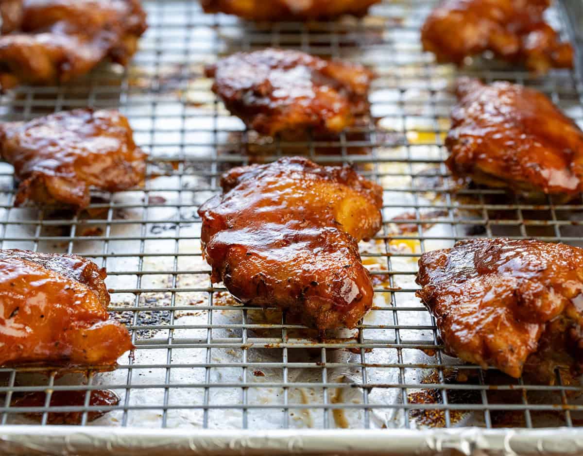 Oven Baked BBQ Chicken Thighs on a rack on a sheet pan just out of the oven after baking.