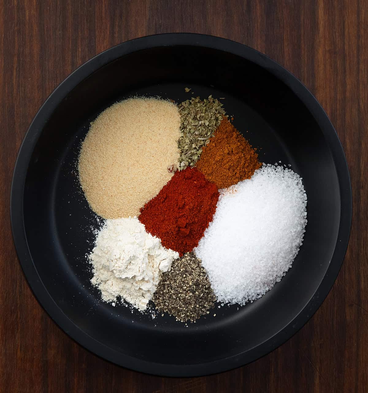 This homemade Potato Seasoning is a simple, savory blend that takes roasted, baked, or air-fried potatoes to the next level! Black bowl filled with Potato Seasoning ingredients before they are mixed.
