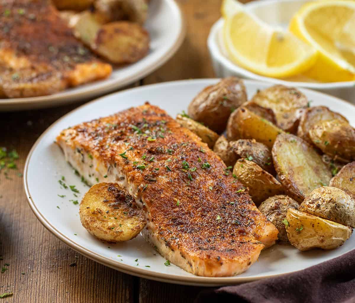 Plates of Salmon and Crispy Potatoes on a wooden table Plates of Salmon and Crispy Potatoes on a wooden table.