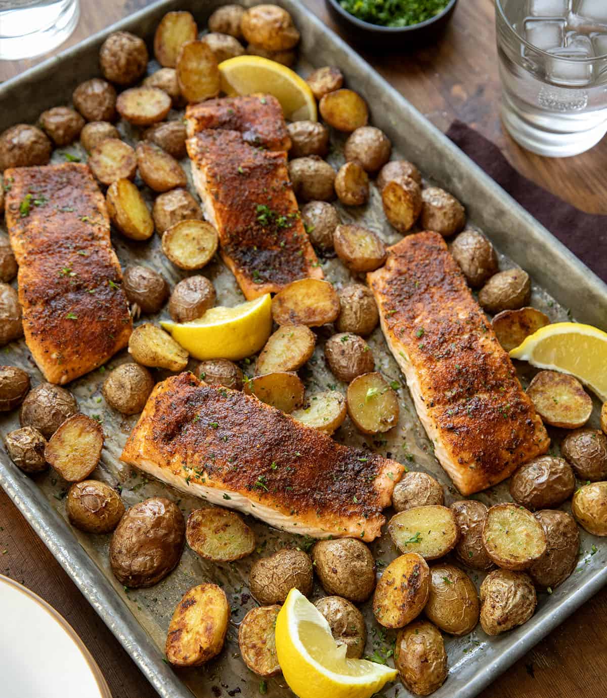 Sheet Pan of Salmon and Crispy Potatoes on a wooden table Sheet Pan of Salmon and Crispy Potatoes on a wooden table.
