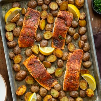 Sheet pan of Salmon and Crispy Potatoes on a wooden table from overhead.