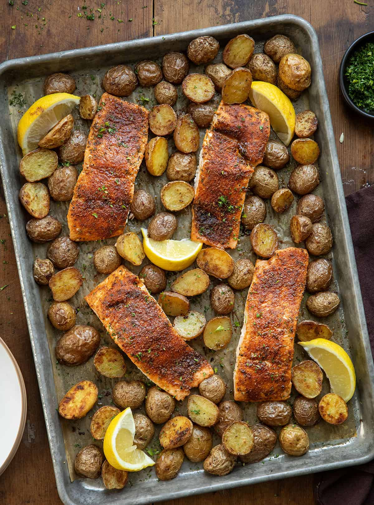 Sheet pan of Salmon and Crispy Potatoes on a wooden table from overhead Sheet pan of Salmon and Crispy Potatoes on a wooden table from overhead.