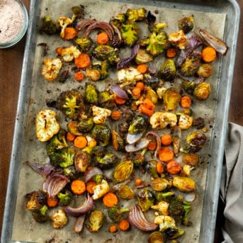 Sheet Pan Roasted Vegetables on a wooden table with a jar of vegetable seasoning from overhead.