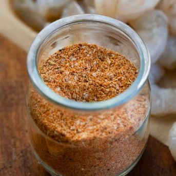 Close up of a jar of Shrimp Seasoning in front of raw shrimp.