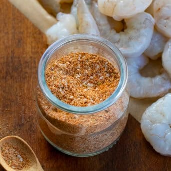 Close up of a jar of Shrimp Seasoning in front of raw shrimp.