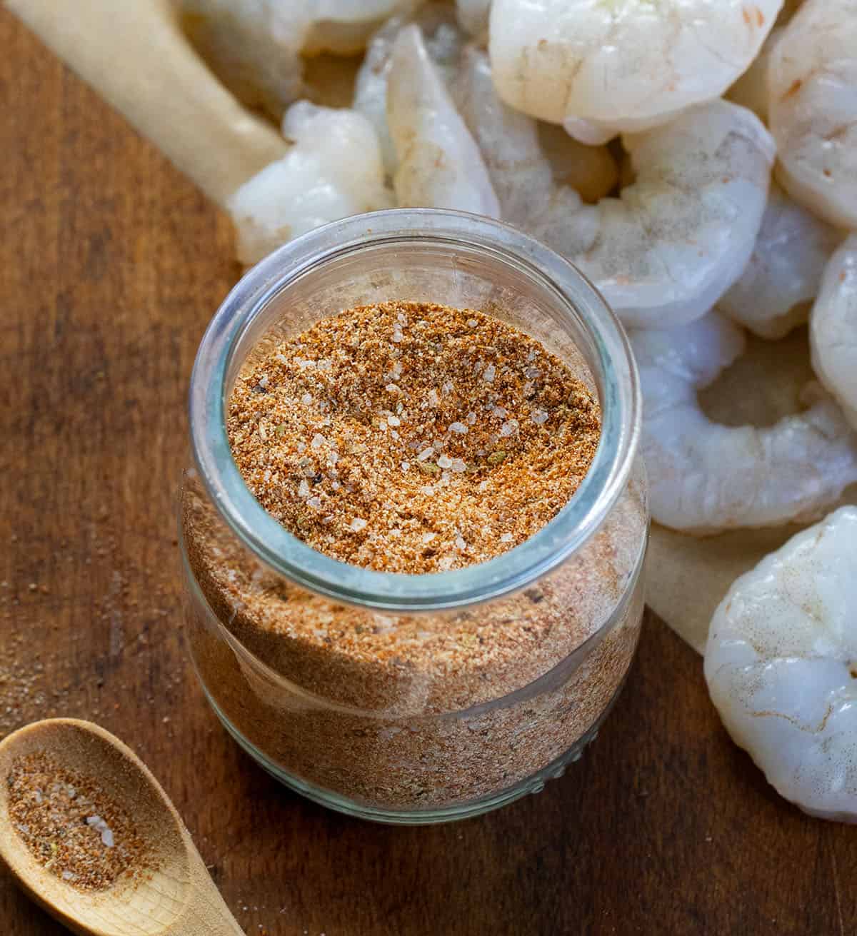 Close up of a jar of Shrimp Seasoning in front of raw shrimp Close up of a jar of Shrimp Seasoning in front of raw shrimp.