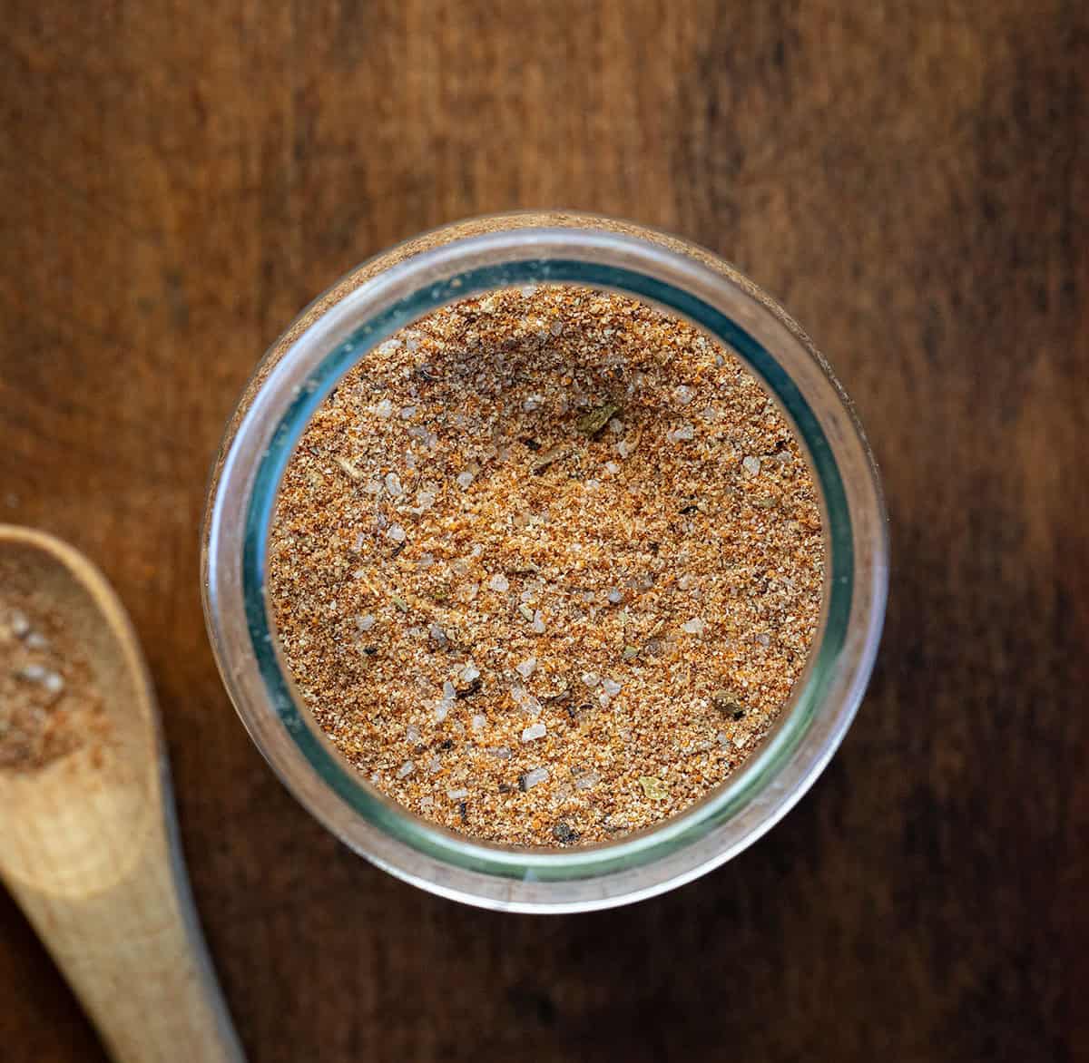 Looking down on a jar of Shrimp Seasoning on a wooden table with wooden measuring spoon Looking down on a jar of Shrimp Seasoning on a wooden table with wooden measuring spoon.