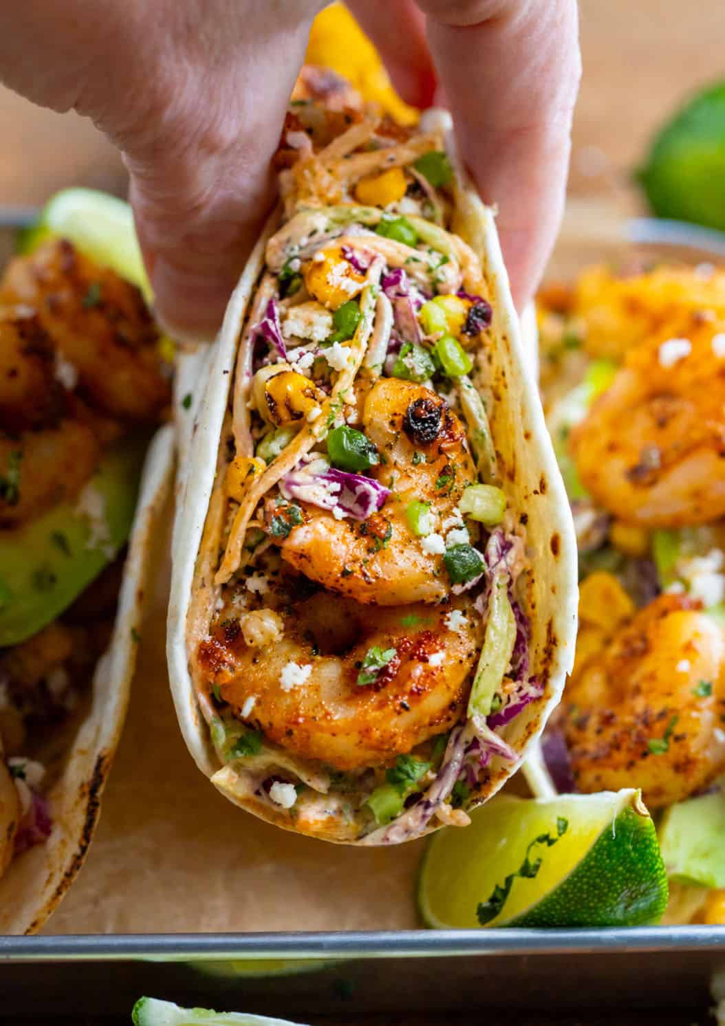 Hand holding a Shrimp Taco with Mexican Street Corn Slaw.