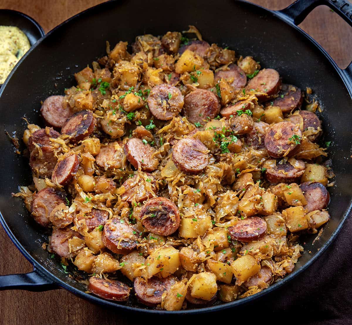 Skillet of Skillet Kielbasa and Sauerkraut on a wooden table Skillet of Skillet Kielbasa and Sauerkraut on a wooden table.