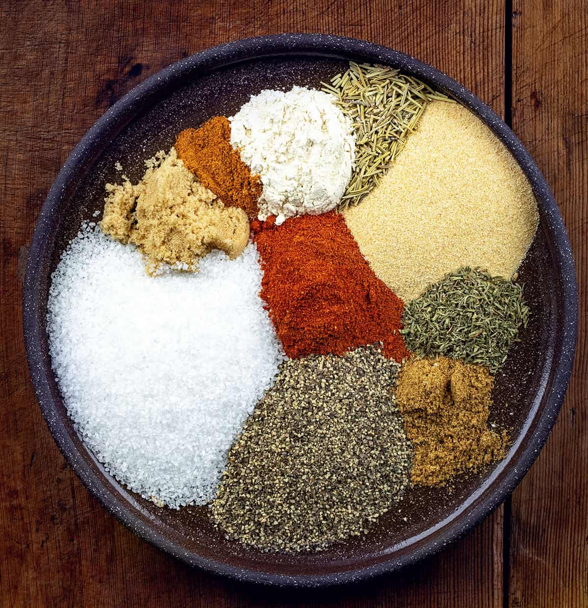 This homemade steak seasoning is bold, savory, and packed with classic steakhouse flavor in every pinch. Keep a jar on hand and you’ll never need store-bought seasoning again! Raw ingredients for Steak Seasoning on a plate on a wooden table.
