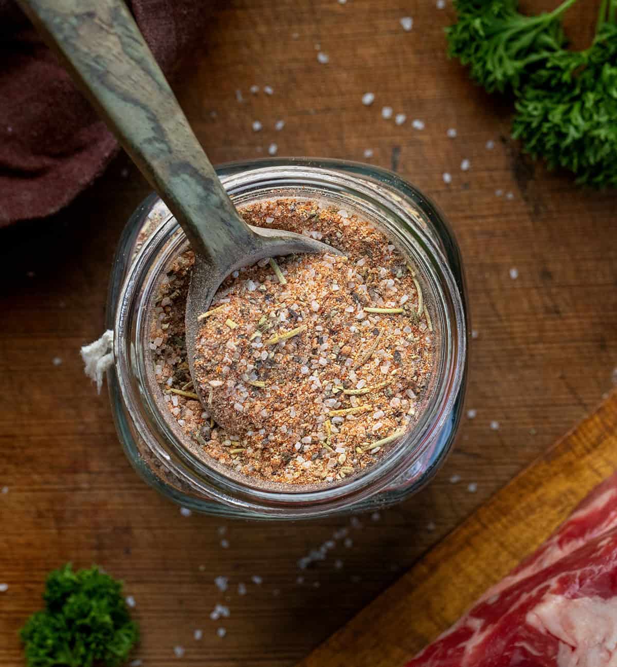 This homemade steak seasoning is bold, savory, and packed with classic steakhouse flavor in every pinch. Keep a jar on hand and you’ll never need store-bought seasoning again! Looking down on a glass jar of Steak Seasoning on a wooden table next to a steak.