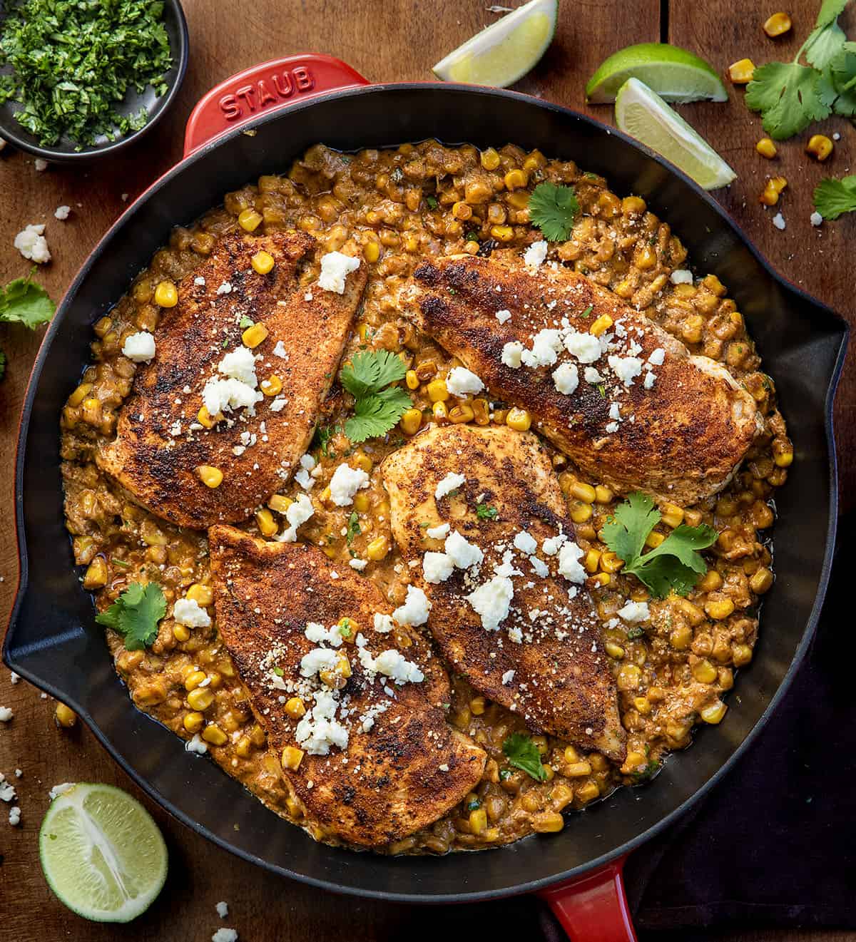 If you love Mexican street corn (elote), you are going to flip for this Creamy Street Corn Chicken Skillet! Juicy seasoned chicken is smothered in a rich, cheesy corn sauce with lime, Cotija, and just the right kick Street Corn Chicken Skillet on a wooden table from overhead.