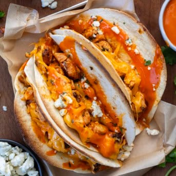 Baked Buffalo Chicken Tacos on a plate on a wooden table from overhead.