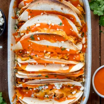 Baked Buffalo Chicken Tacos in a baking dish on a wooden table.