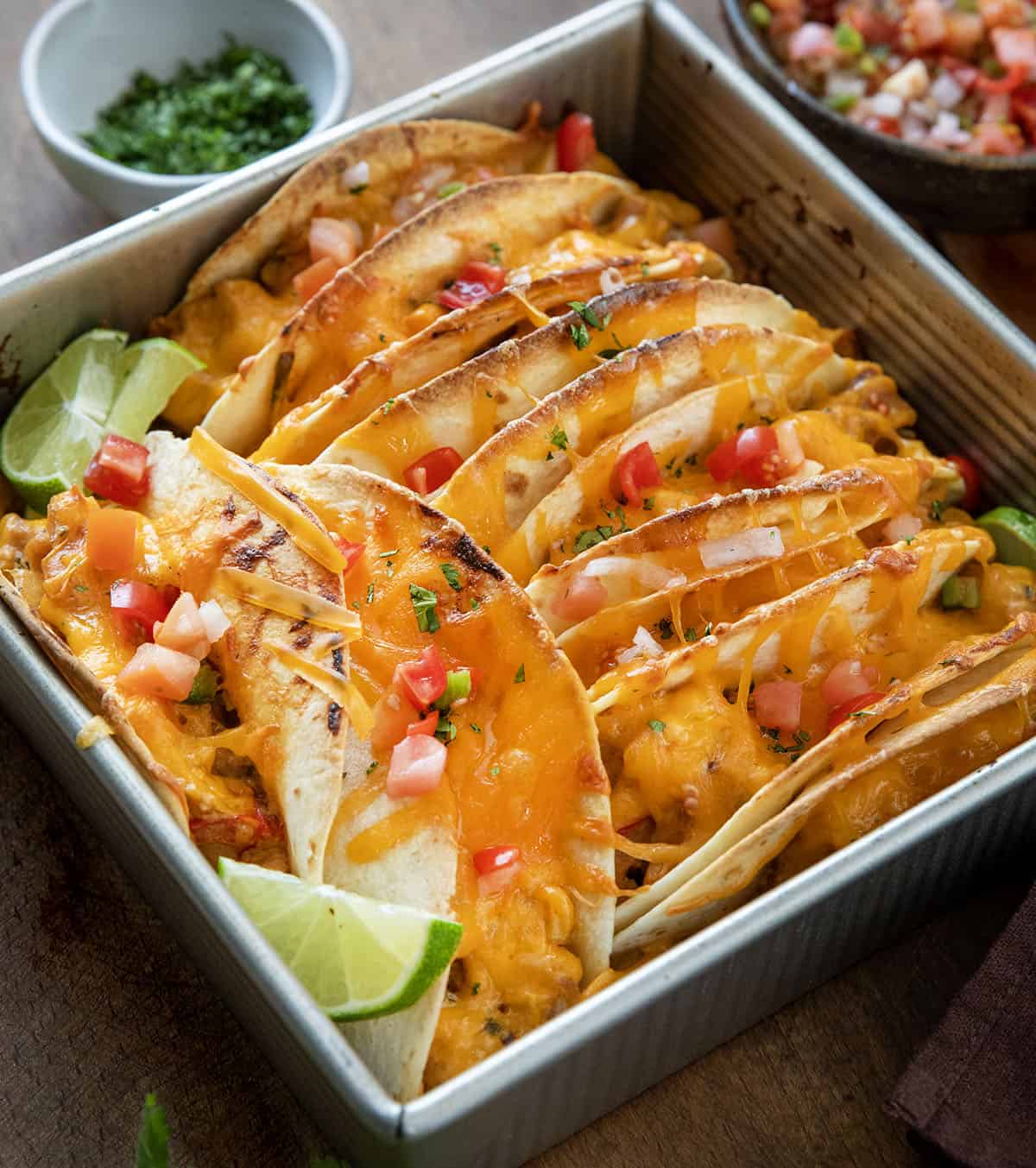 Baked Chicken Tacos in a pan on a wooden table with fresh lime.