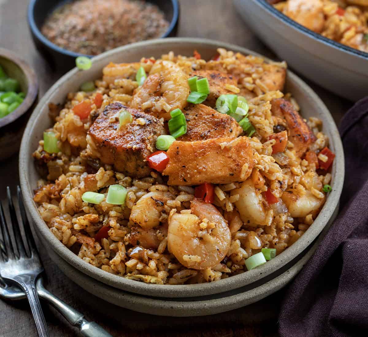 Plates of Cajun Salmon and Shrimp Fried Rice on a wooden table very close Plates of Cajun Salmon and Shrimp Fried Rice on a wooden table very close.