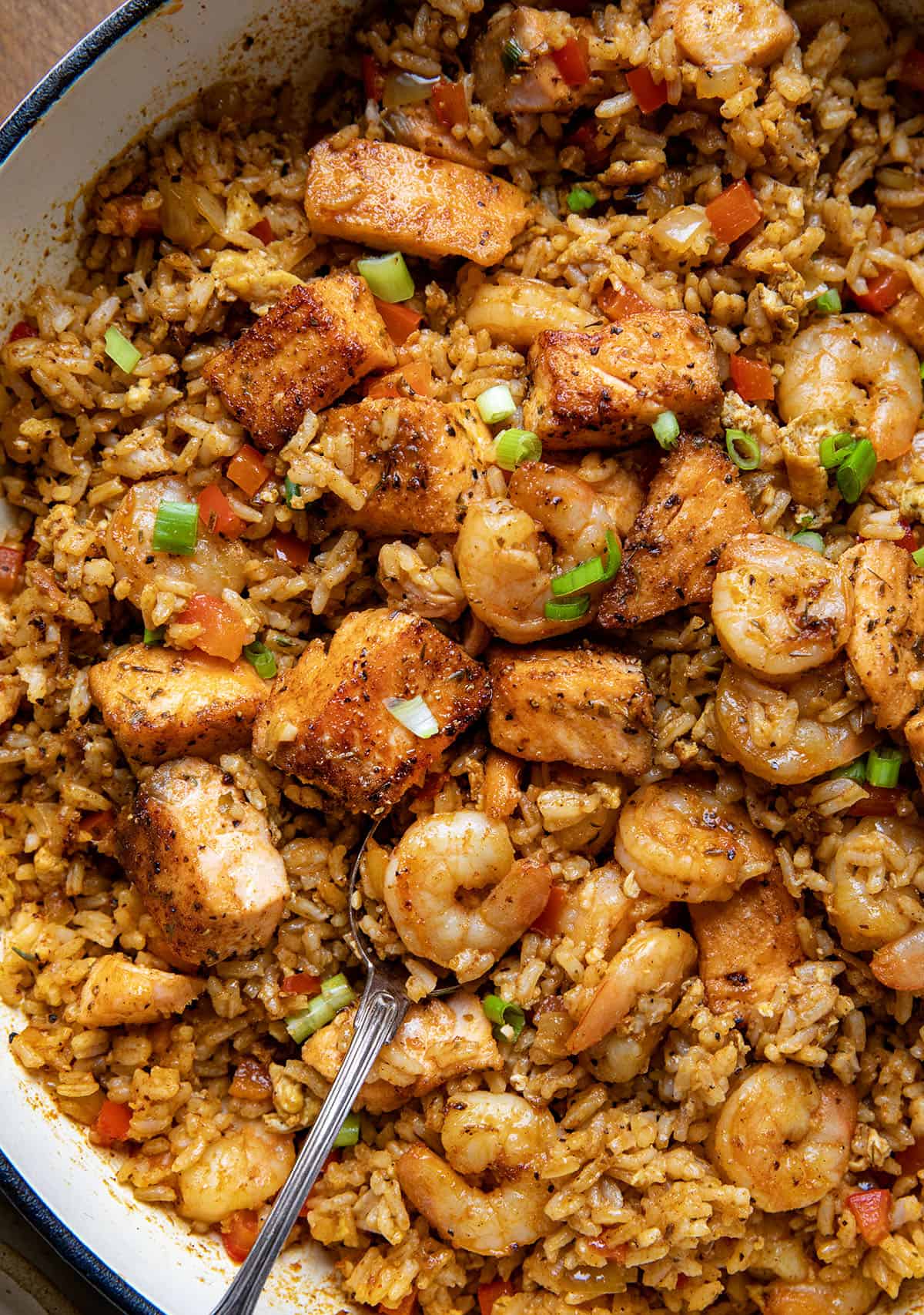 Skillet of Cajun Salmon and Shrimp Fried Rice with a spoon in it Skillet of Cajun Salmon and Shrimp Fried Rice with a spoon in it.