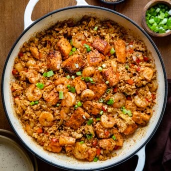 Skillet of Cajun Salmon and Shrimp Fried Rice on a wooden table from overhead.