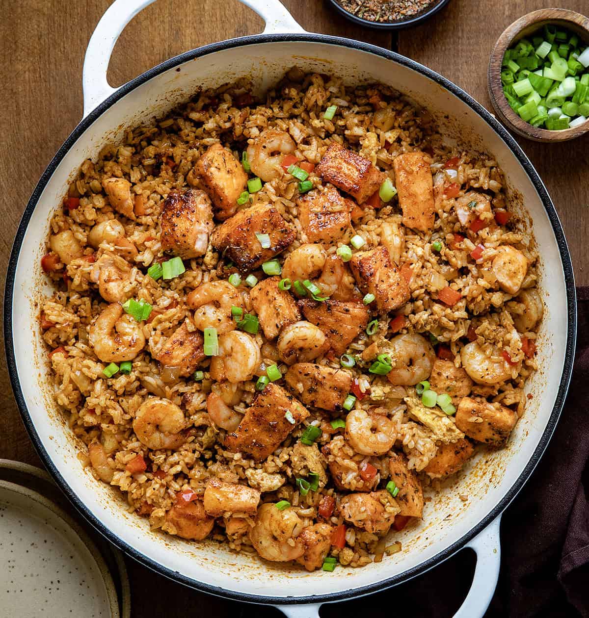 Skillet of Cajun Salmon and Shrimp Fried Rice on a wooden table from overhead Skillet of Cajun Salmon and Shrimp Fried Rice on a wooden table from overhead.
