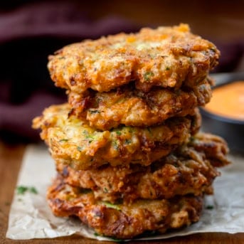 Stack of Cheesy Zucchini Chicken Fritters on a wooden table close up.