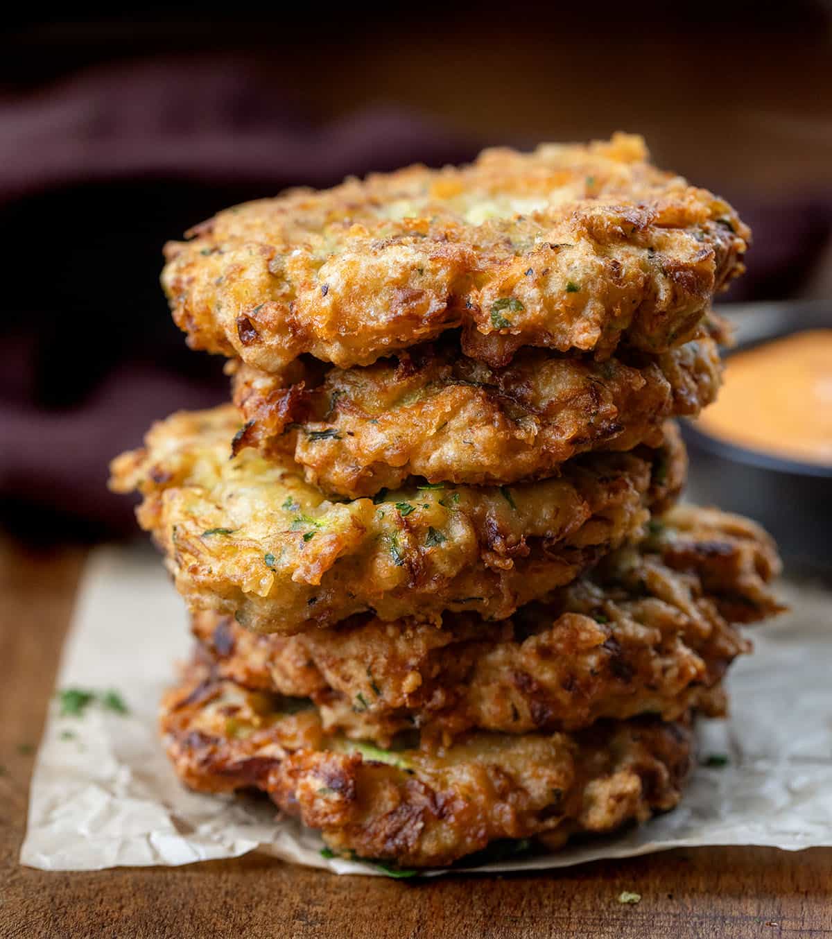 Stack of Cheesy Zucchini Chicken Fritters on a wooden table close up.
