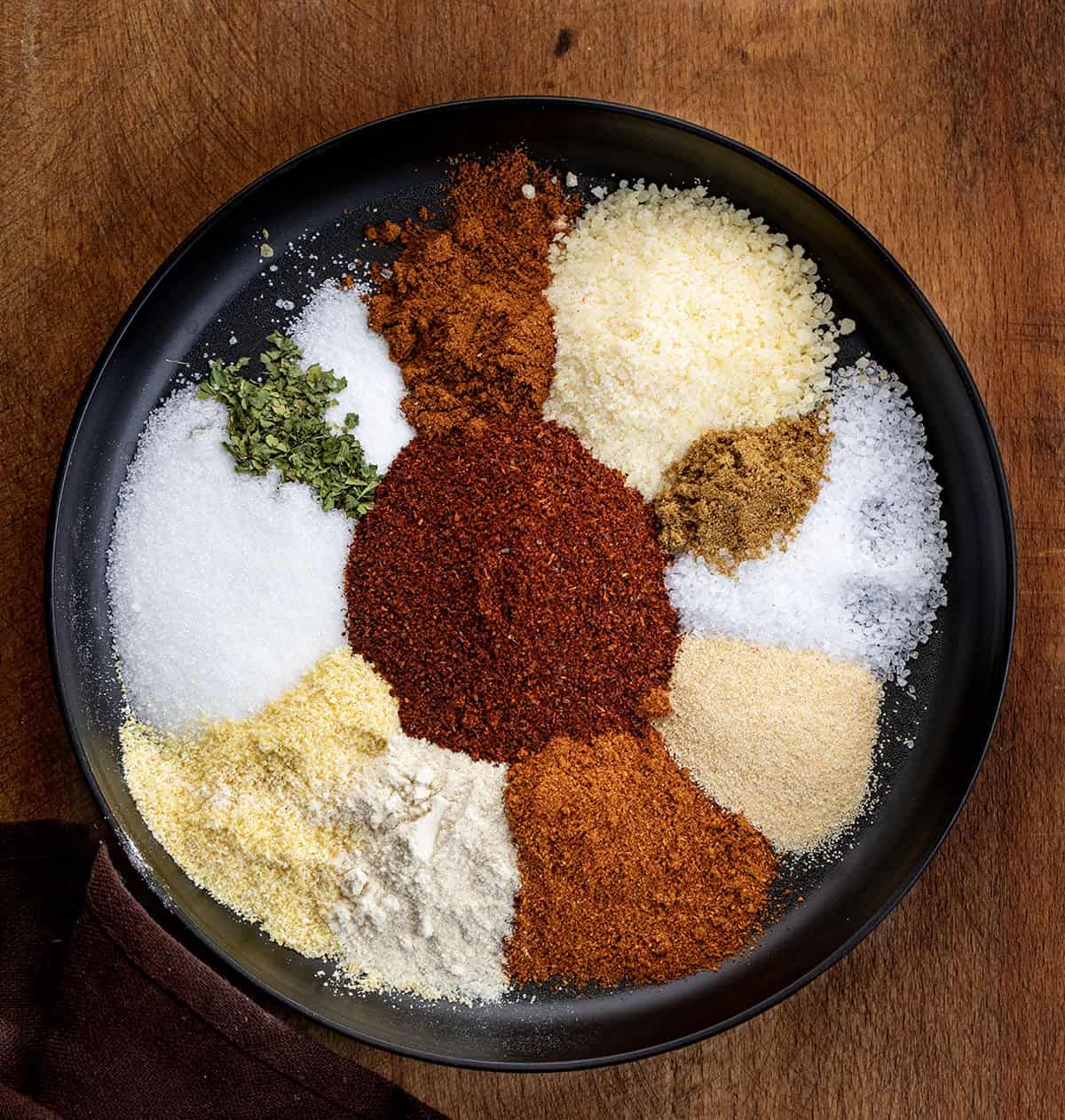All of the raw seasonings for Elote Seasoning Mix on a black plate before being mixed All of the raw seasonings for Elote Seasoning Mix on a black plate before being mixed.